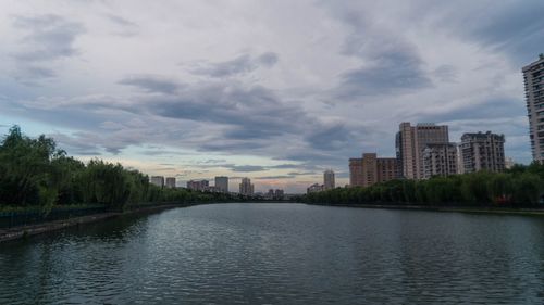 River with buildings in background against cloudy sky