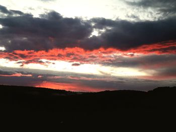 Silhouette landscape against dramatic sky during sunset