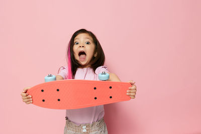 Portrait of smiling girl holding skateboard