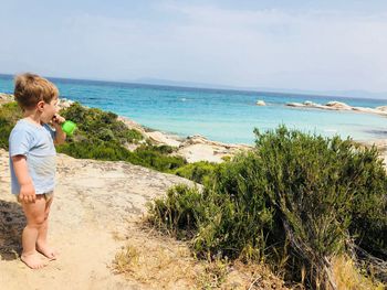 Full length of boy holding toy while standing at beach against sky