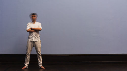 Blurred motion of man shaking head while standing against white wall