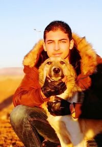 Portrait of man with dog against sky