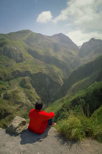 Rear view of man looking at mountains against sky