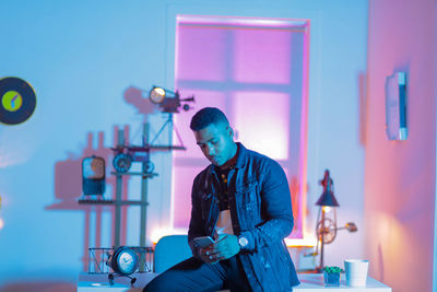 Young man holding glass while sitting on table