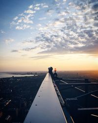 Man in city against sky during sunset