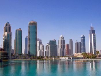 Modern buildings by swimming pool against blue sky