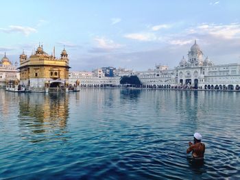 Rear view of man praying in pond at golden temple