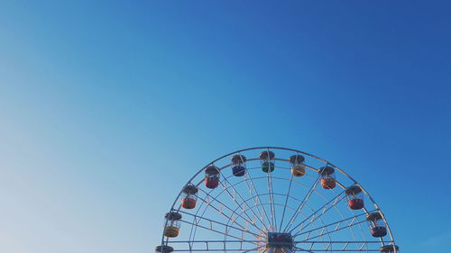 Low angle view of ferris wheel against blue sky