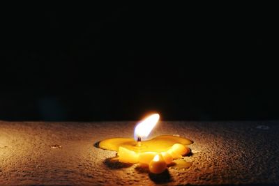 Close-up of lit candle in darkroom