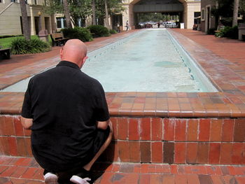 Rear view of man standing on footpath by building