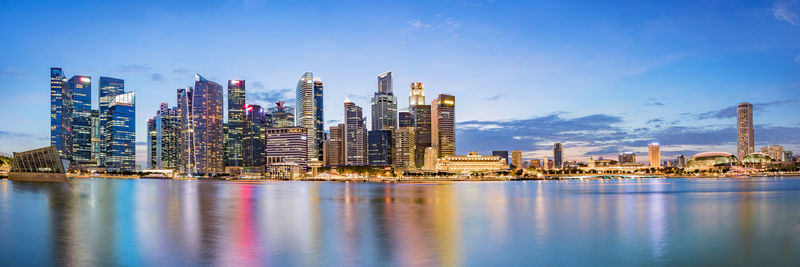 Modern buildings by river against sky in city