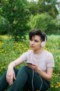 Young woman in headphones and with smartphone using audio chat social networking app, 