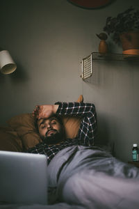 Sick man having online consultation on laptop while lying on bed