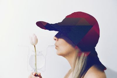 Side view of young woman with tulip against white background