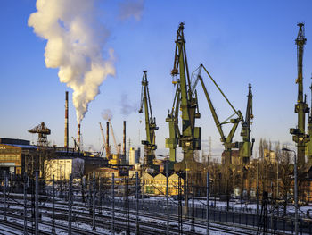 Smoke emitting from factory against sky