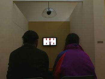 Rear view of man and woman standing against illuminated clock