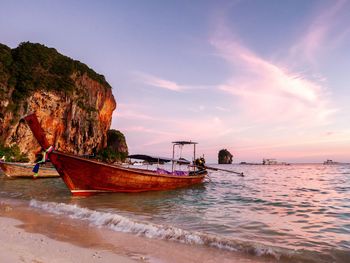 Boat moored on beach against sky during sunset