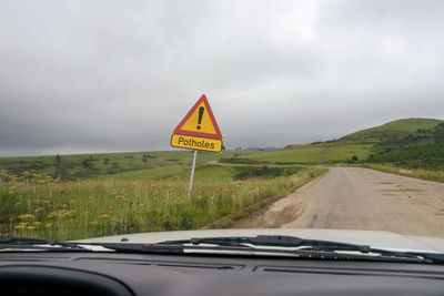 Road sign against sky seen through car windshield