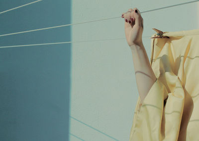 Cropped hand of woman holding clothesline during sunny day