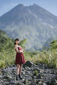 Full length of woman standing on rocks against mountain