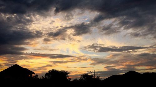 Silhouette houses against sky during sunset