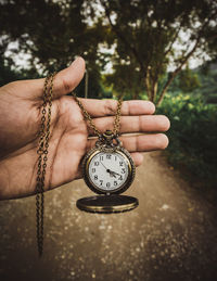 Cropped hand holding pocket watch