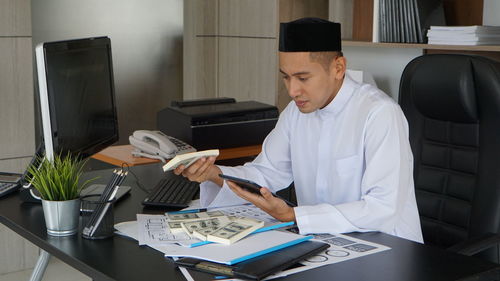 Young man using laptop at desk in office