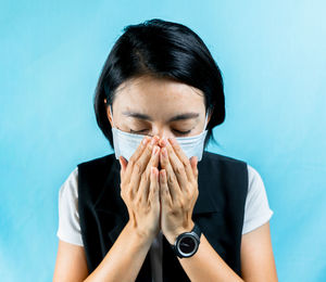Portrait of young woman against blue background