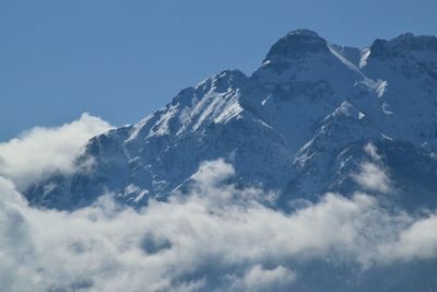 Low angle view of snowcapped mountains against blue sky