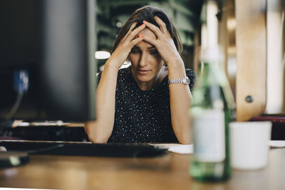 Frustrated female computer programmer with head in hands at office desk