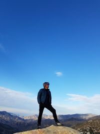 Full length of man standing on mountain against blue sky