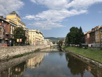 Canal amidst buildings in town against sky