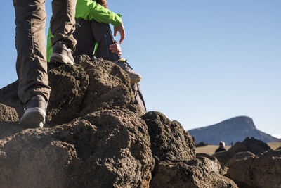 Low section of people on rock against sky