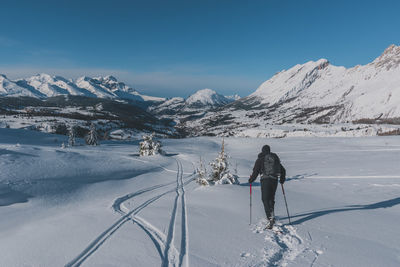 An unrecognizable male hiker wearing snowshoes walking in the french alps