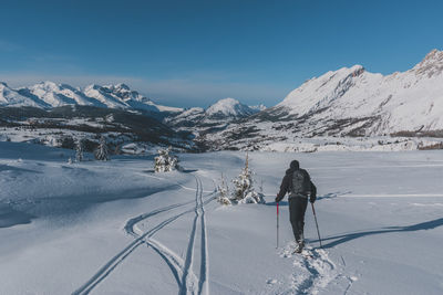 Rear view of man walking on snow covered mountain