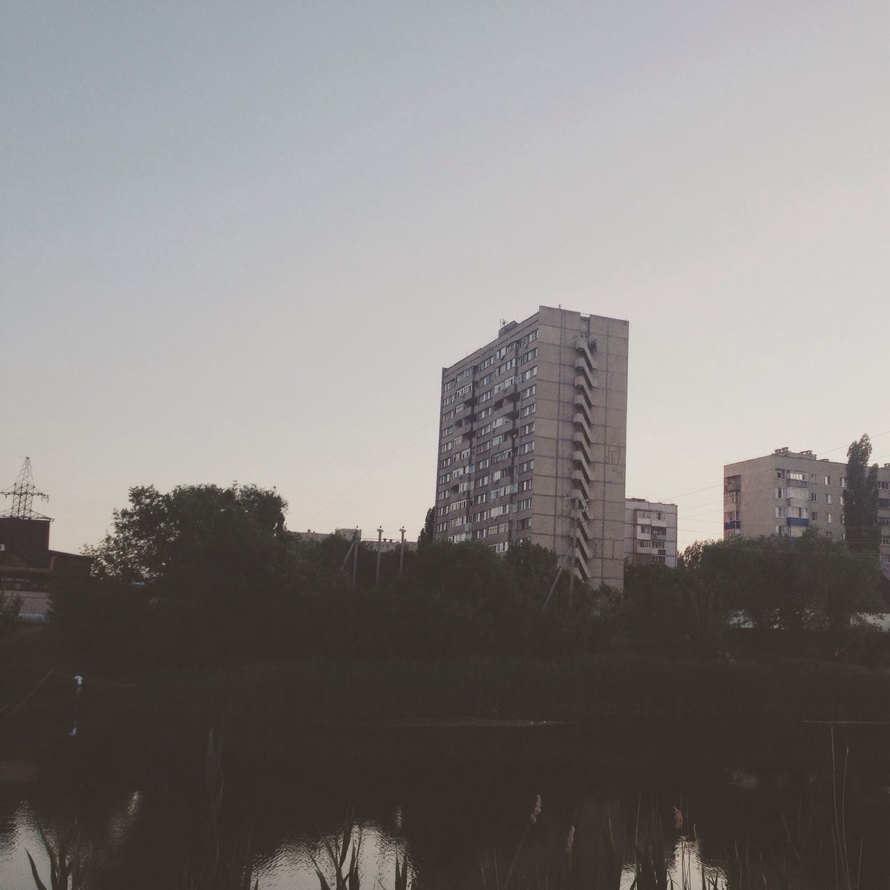 building exterior, architecture, built structure, clear sky, city, tree, reflection, water, skyscraper, copy space, tall - high, lake, river, sky, building, cityscape, tower, growth, waterfront, no people