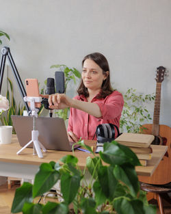 Portrait of smiling young woman using mobile phone while sitting at home