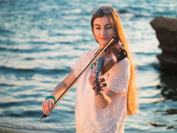 Close-up of young woman playing the violin at seaside