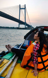 Woman on bridge over river against sky during sunset