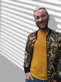 Portrait of smiling man standing against wall