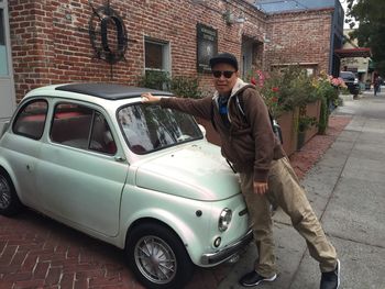 Man standing by car in city