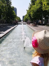 Rear view of woman with umbrella in canal amidst trees