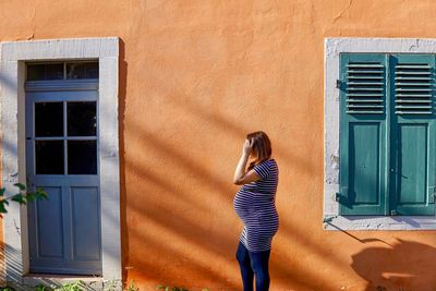 Woman standing by window of building