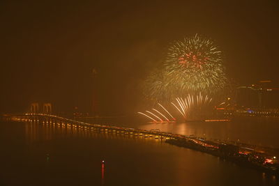 Firework display over river against sky at night