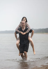 Young couple having fun on the beach at runny summer day