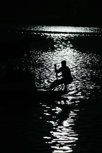 Silhouette people in water at sunset