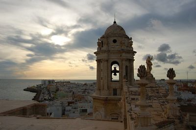 Bell tower by sea during sunset