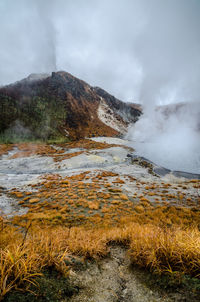 Scenic view of mountain by hot spring against sky