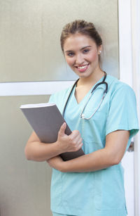Nurse with stethoscope and file wearing scrubs while working in hospital