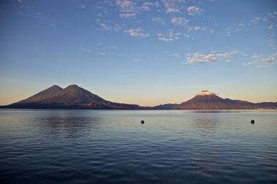 Scenic view of sea and mountains against blue sky